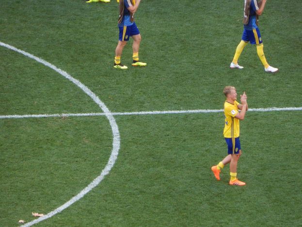 Mannergruppe in Fußballtrikots klatscht feierlich auf einem Fußballfeld.