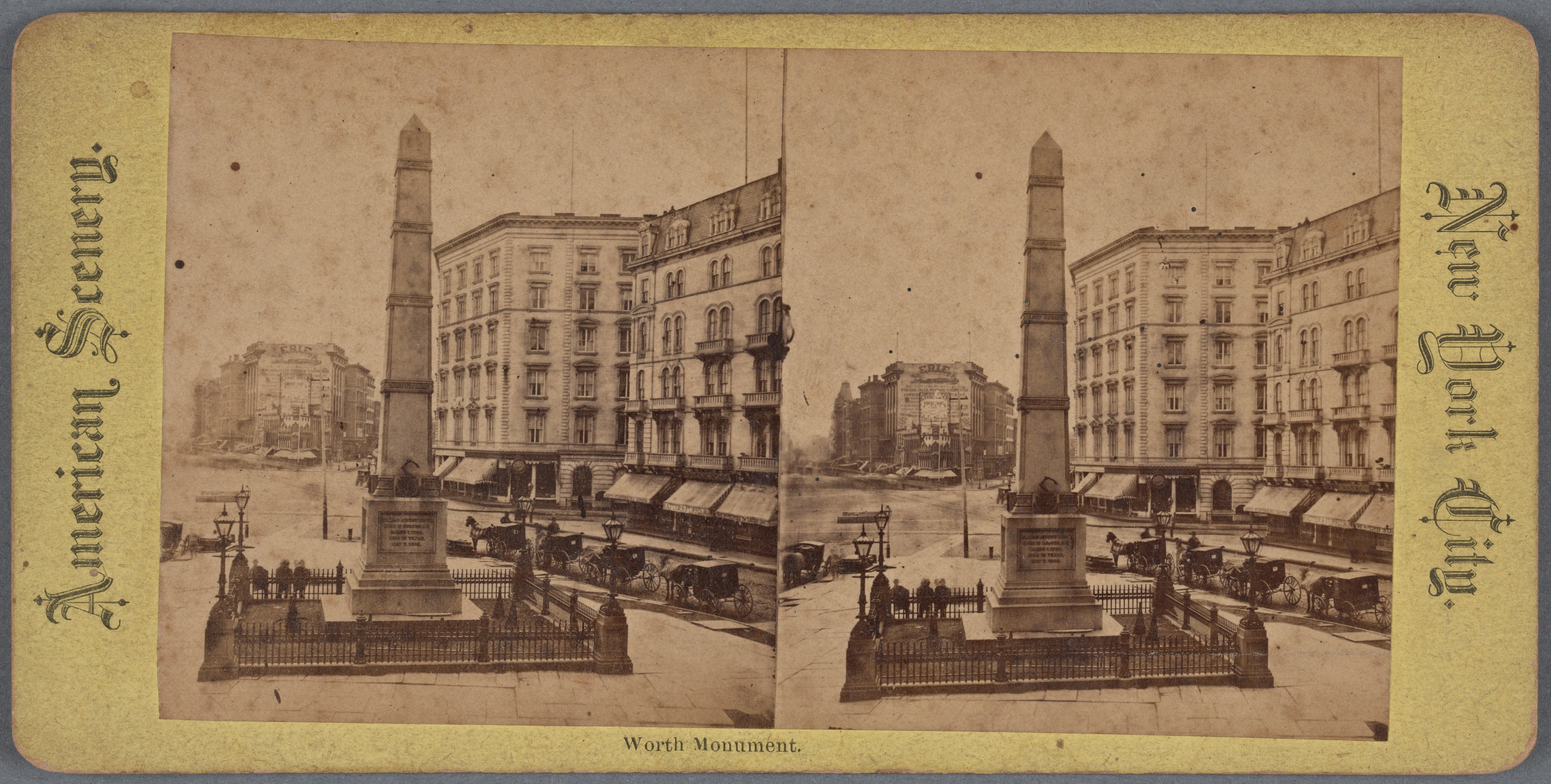 Altes Schwarz-Weiß-Foto einer Stadtstraße mit einem zentralen Denkmal umgeben von Gebäuden, Straßenmöbeln, parkenden und fahrenden Fahrzeugen, Fußgängern auf dem Gehweg und einem sichtbaren Himmel.