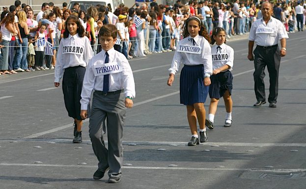Eine Gruppe von Menschen, die auf einer Straße gehen und Abzeichen auf ihren Hemden tragen, mit einer großen Menge, die sich um die Straße versammelt hat.