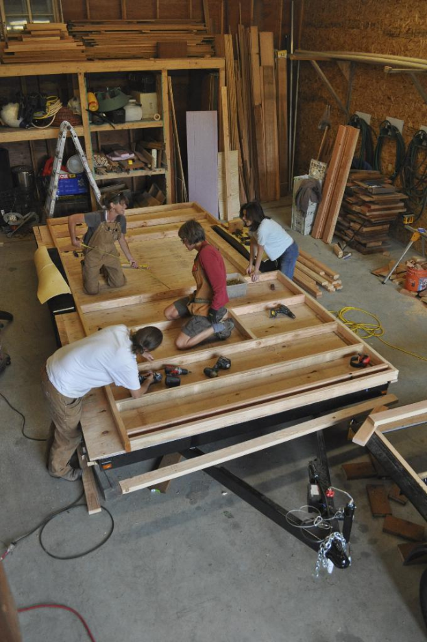 Eine Schreinerwerkstatt mit mehreren Arbeitern, umgeben von Werkzeugen und Materialien.