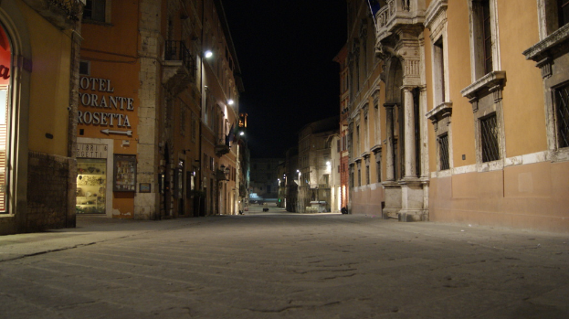 Eine Nachtansicht einer Straße mit Geböuden auf beiden Seiten und einem Laden auf der linken Seite.