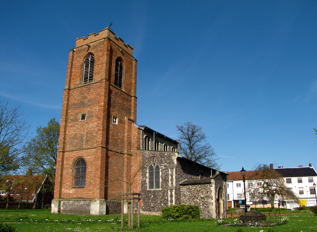 Eine grüne Fläche mit einem Pfahl, umgeben von Gebäuden und Bäumen.