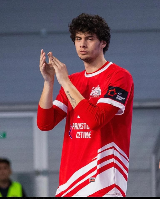 Mann in rot-weißem Hemd klatscht in den Händen vorne, mit einer anderen Person und einer Wand im Hintergrund und Text 'Kopenhagen Futsal Club - Foto 1' unten.
