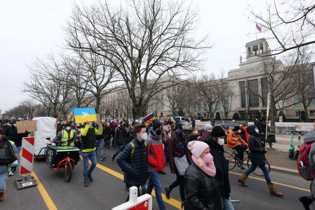 Eine große Gruppe von Menschen marschiert auf einer Straße in Washington, D.C. am 21. Januar 2020 mit Schildern und Transparenten, einige fahren Fahrräder, mit Bäumen und einem klaren blauen Himmel im Hintergrund.