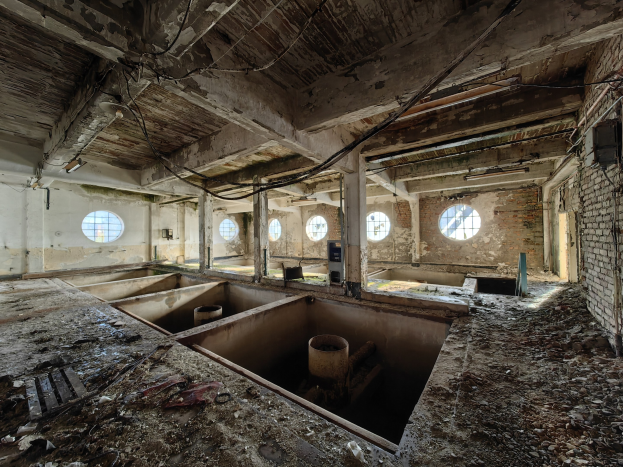 Verlassener Gebäuderaum im Sperrgebiet von Tschernobyl mit verstreuten Trümmern, freiliegenden Wänden, Decke und strukturellen Elementen.