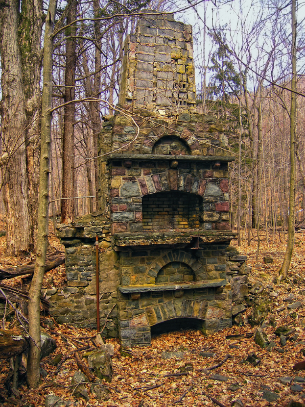Ein Ziegelgebäude mit Bäumen im Hintergrund und Felsen am Boden.