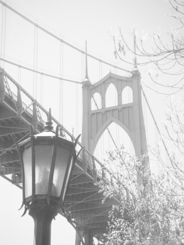 Ein altes Bild einer Hängebrücke mit einem schwarzen Laternenmast vorne unten und einem Baum in der rechten Ecke.