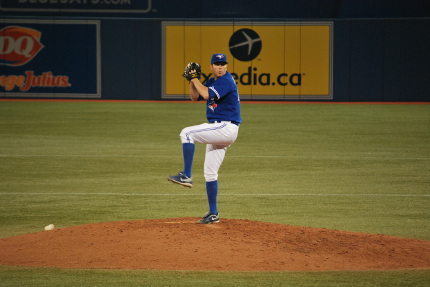 Ein Spieler steht auf dem Boden und hält einen Ball, mit einem großen Banner mit Text und Bildern im Hintergrund.