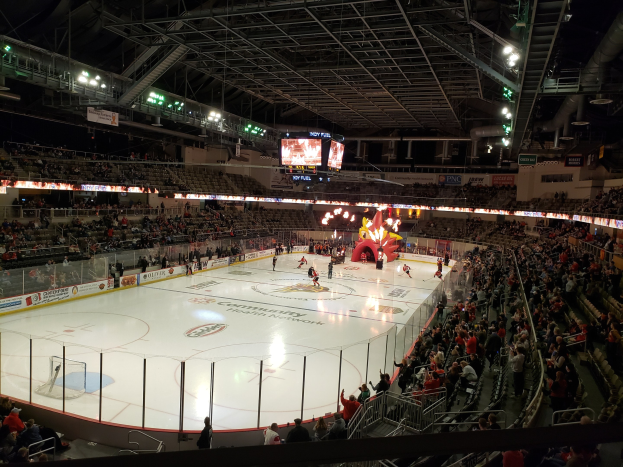 Eishockeyspiel in einer großen Arena mit Zuschauern, eine von einem Zaun umgebene Eisfläche, Banner, Deckenbeleuchtung und zwei Bildschirme; die Location ist die Columbus Blue Jackets Arena.