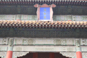 Der Eingang zur verbotenen Stadt in Peking, China, mit einem Gebäude mit detaillierten Entwürfen, Säulen und einer Tafel mit Text.