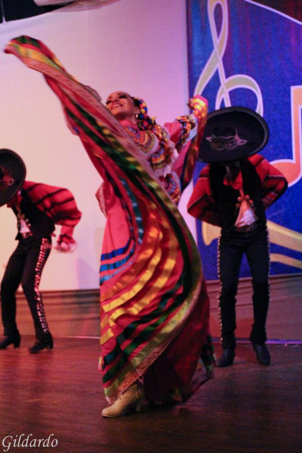 Menschen stehen auf einer Bühne in Kostümen, mit einem Vorhang mit einem Bild im Hintergrund.