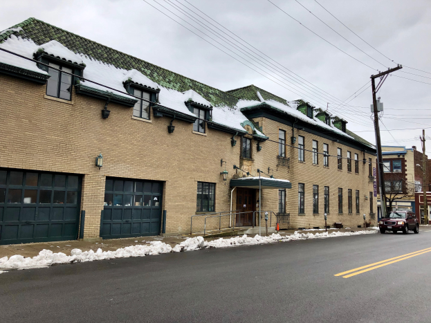 Ein großes Backsteingebäude mit einem grünen Dach an einer Straßenecke, umgeben von Fahrzeugen, Schnee, Strommasten, Bäumen und einem bewölkten Himmel, identifiziert als das ehemalige St. Louis Fire Station.