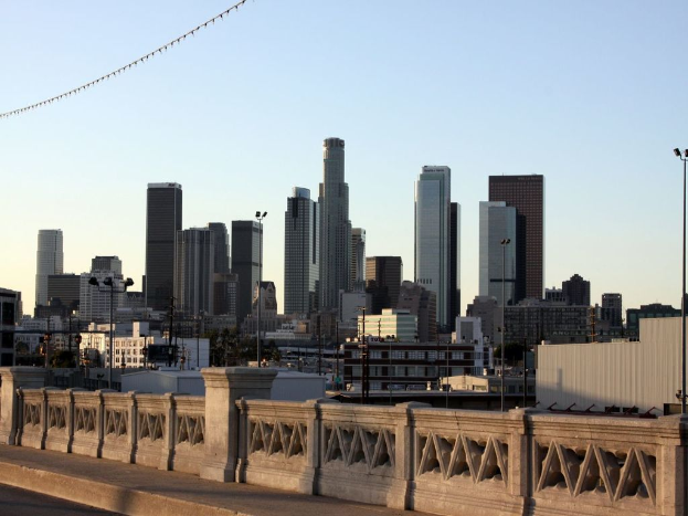 Ein Geländer im Vordergrund mit hohen Gebäuden und Masten dahinter.