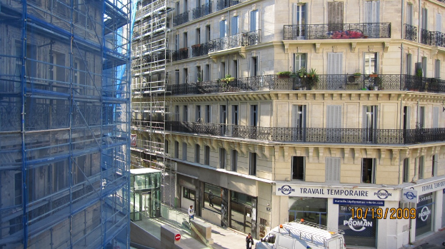 Ein gro√ües Geb√§ude mit einem Laden im Erdgeschoss und Bauarbeiten auf der linken Seite.