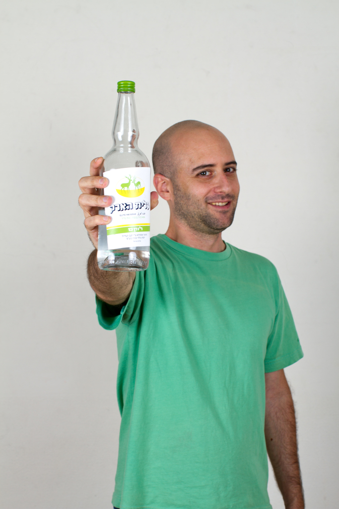 Ein Mann, der lachend eine Flasche in der Hand hält.