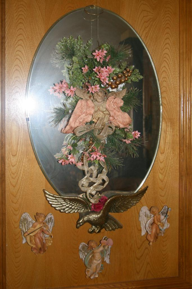 Eine hölzerne Fläche mit Skulpturen, darunter eine Vogelskulptur und Verzierungen mit Blumen, Blättern und Bändern.