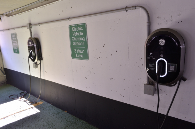 Elektrofahrzeug-Ladestationen an einer Wand in einer Parkgarage mit Informationsschildern darunter.