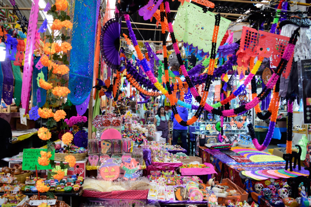 Ein belebter Markt mit Ständen, die Spielzeug, Dekorationsartikel und andere Gegenstände verkaufen, unter einer Decke, die mit Lichtern geschmückt ist, mit Menschen, die umherlaufen.