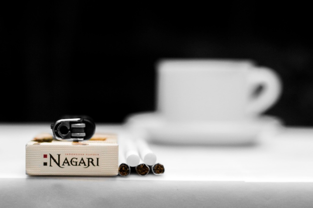 Eine Tasse und Untertasse, Zigaretten, Abfall und eine Box sind auf einem Tisch.