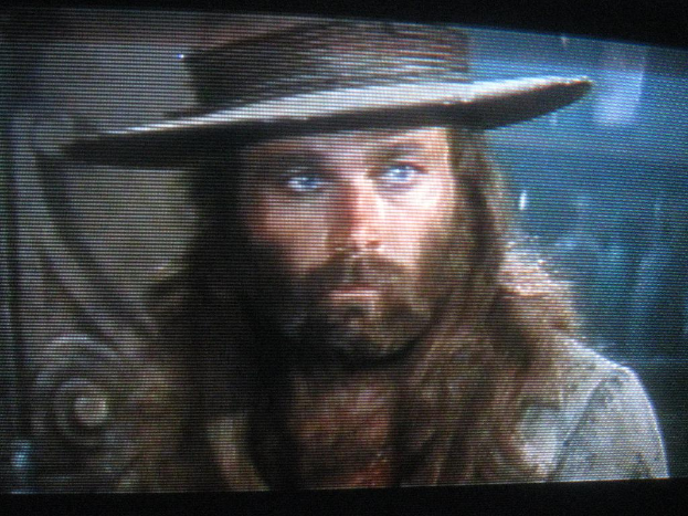 Ein Mann mit Bart und Schnurrbart trägt auf einem Bild einen Hut.