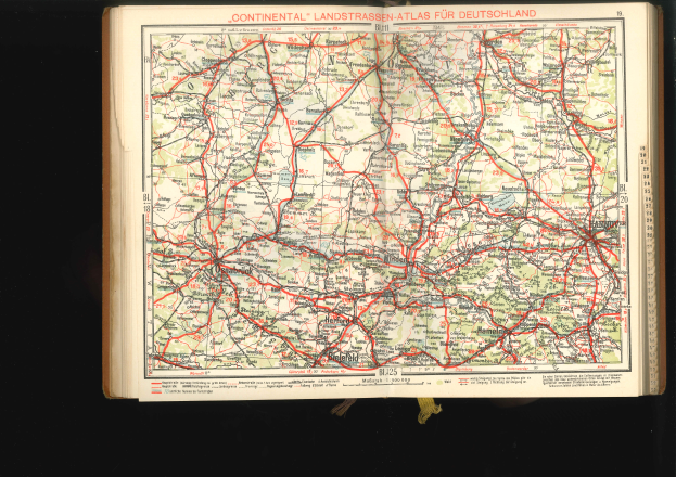 Ein aufgeschlagenes Buch mit einer detaillierten Deutschlandkarte mit Straßen und Autobahnen, vor einem schwarzen Hintergrund.