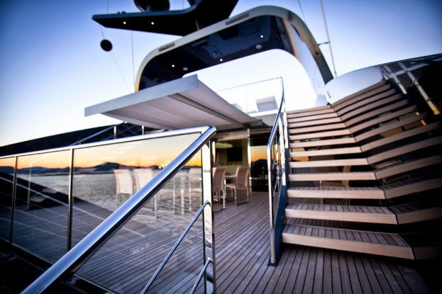 Ein modernes Gläserne Gebäude mit Treppen auf der rechten Seite, Stühle um einen Tisch auf der linken Seite und ein Glasgeländer links unten.