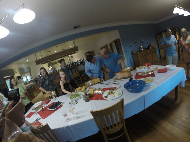 Eine Gruppe von Menschen steht in einem Raum mit einem weißen Mitteltisch, der mit Essen gedeckt ist.