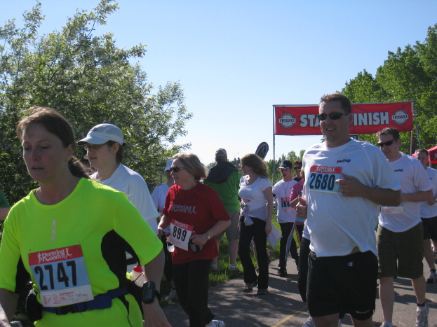 Eine Gruppe von Kindern läuft bei einem Marathon, mit einem roten Banner und Bäumen im Hintergrund.