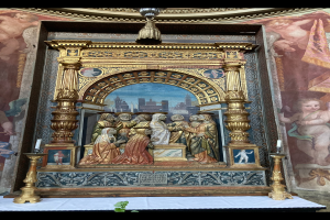 Ein Altar in einer Kirche mit Skulpturen, Kerzen und verschiedenen Gegenständen, vor einer Wand mit einem Gemälde und einer Pflanze unten für Grün