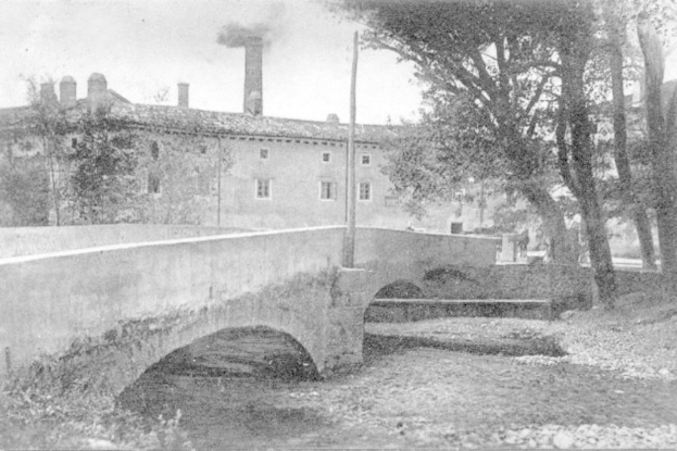 Eine Szene mit Gebäuden und Bäumen, einem Pfahl und einer Brücke im Vordergrund, Wasser unten und Rauch, der aus der Schornsteinspitze aufsteigt