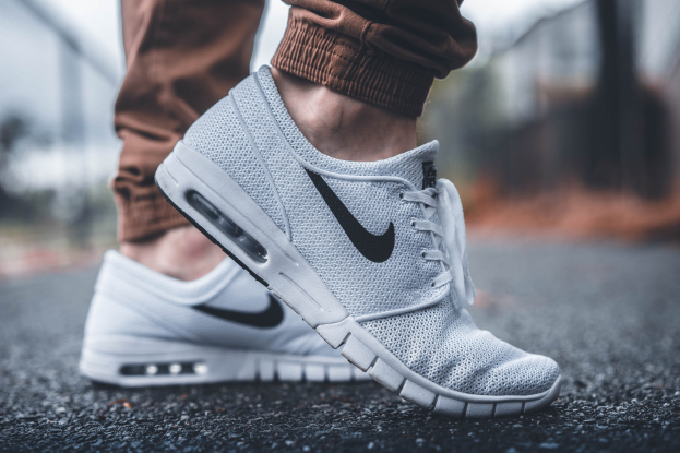 Nahaufnahme einer Person, die Nike SB Stefan Janoski Max Schuhe in Wolf Grey/Black-White trägt, mit einem unscharfen, träumerischen Hintergrund.