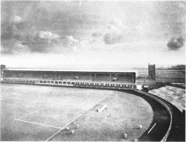 Ein Schwarz-Weiß-Foto eines Fußballfeldes mit einem Stadion, das von Bäumen umgeben ist und ein bewölkter Himmel, mit "Stoke City Football Club" am unteren Rand.