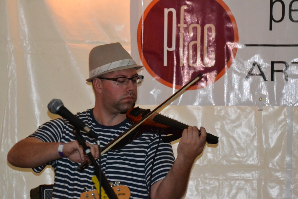 Ein Mann spielt Geige mit einem Mikrofon vor ihm.