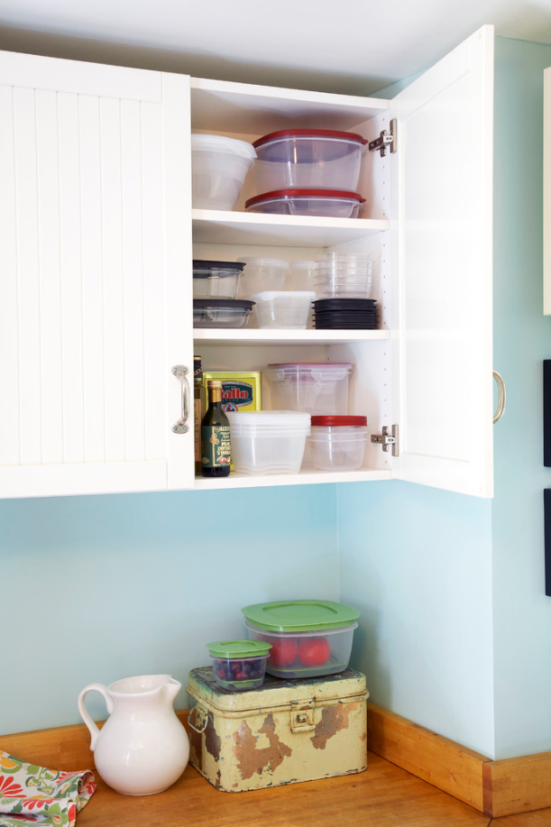 Ein Schrank mit Behältern, einer Flasche und verschiedenen Gegenständen auf seinen Regalen, mit einem weißen Gefäß, Kisten und Gegenständen auf dem Boden.