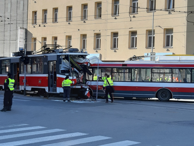 Rote und weiße Straßenbahn krachte an den Straßenrand mit ein paar Menschen in der Nähe und einem Gebäude im Hintergrund.