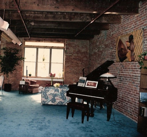 Ein Klavier mit zwei Notizbühchern darauf, ein Glasgemälde und ein Fenster im Hintergrund, mit einem kunstvoll entworfenen Dach.