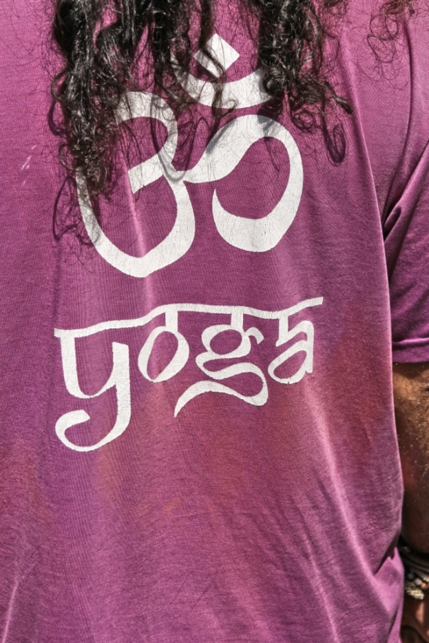 Eine Person in einem pinken T-Shirt mit der Aufschrift "YOGA" und einem Symbol darauf, mit sichtbaren Haaren auf dem Kopf.