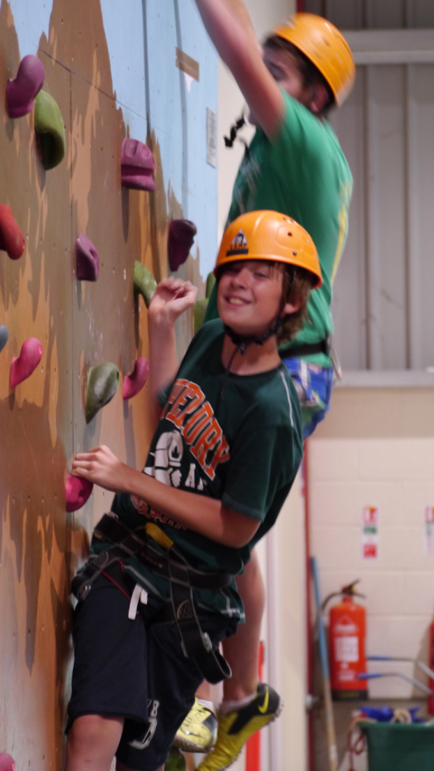 Eine Person klettert an einer Wand hoch, neben ihnen befindet sich ein Feuerlöscher.