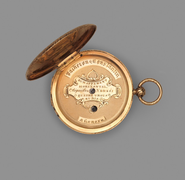 Goldene Taschenuhr mit geschlossenem Deckel auf grauem Hintergrund, mit eingraviertem Text, der wahrscheinlich die Marke oder Art angibt.