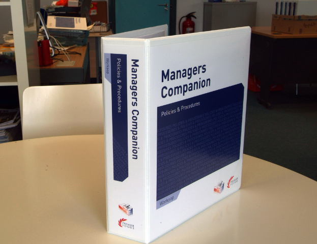 Ein Buch auf einem Tisch mit einem Stuhl dahinter, in der Nähe einer Tür, Feuerlöscher, Akten und anderen Gegenständen.