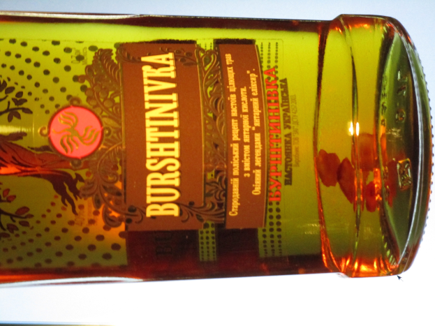 Eine Flasche Olivenöl mit goldbrauner Flüssigkeit steht auf einem Tisch und zeigt ein Etikett.