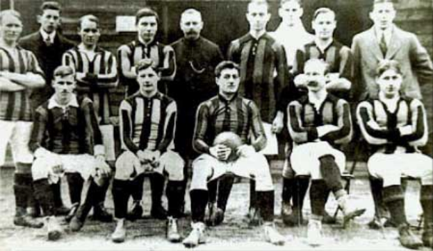 Ein Schwarz-Wei├č-Foto einer Fussballmannschaft, mit einigen stehenden und einigen sitzenden Spielern vor einer Wand, mit dem Text "Ballymena Football Club" unten.