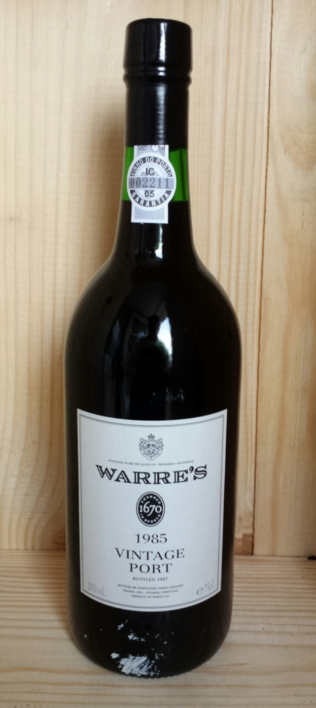 Eine Bierflasche mit Etiketten liegt auf einem Holzweg.