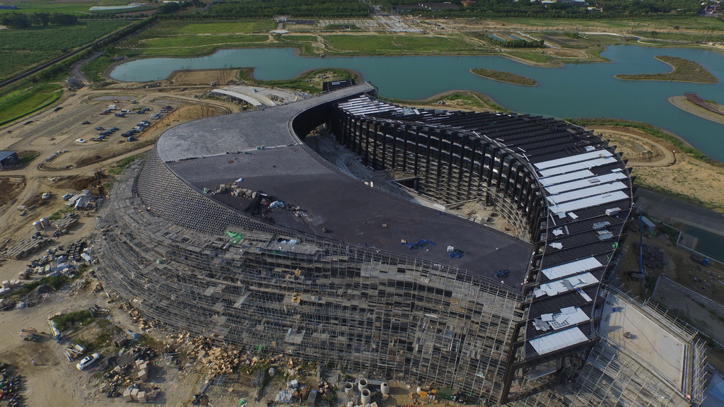 Ein Gebäude, ein Gewässer mit Gras am Ufer und ein parkendes Auto.