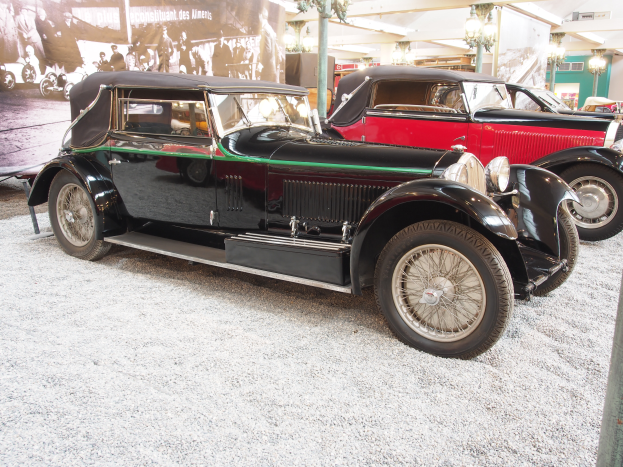 Eine Gruppe von Oldtimern in einem Museum ausgestellt, mit einem Banner auf der linken Seite mit Fotos und Text und an der Decke angebrachten Lichtern im Hintergrund.