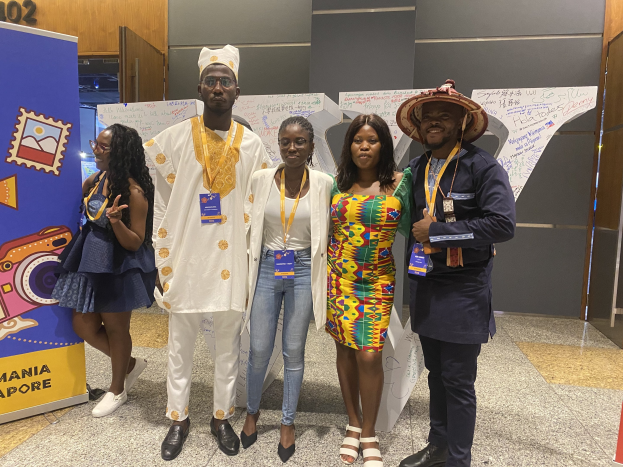 Gruppe von Menschen, die vor einem Schild posen, Namensschilder tragen und lächeln, mit einem Banner links und Event-Tafeln mit der Aufschrift "Nigerian Business Forum 2019: Das Beste aus Nigeria" im Hintergrund.