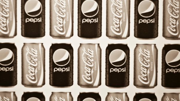 Zwei Dosen Limonade, eine Pepsi und eine Coca-Cola, nebeneinander gestellt.