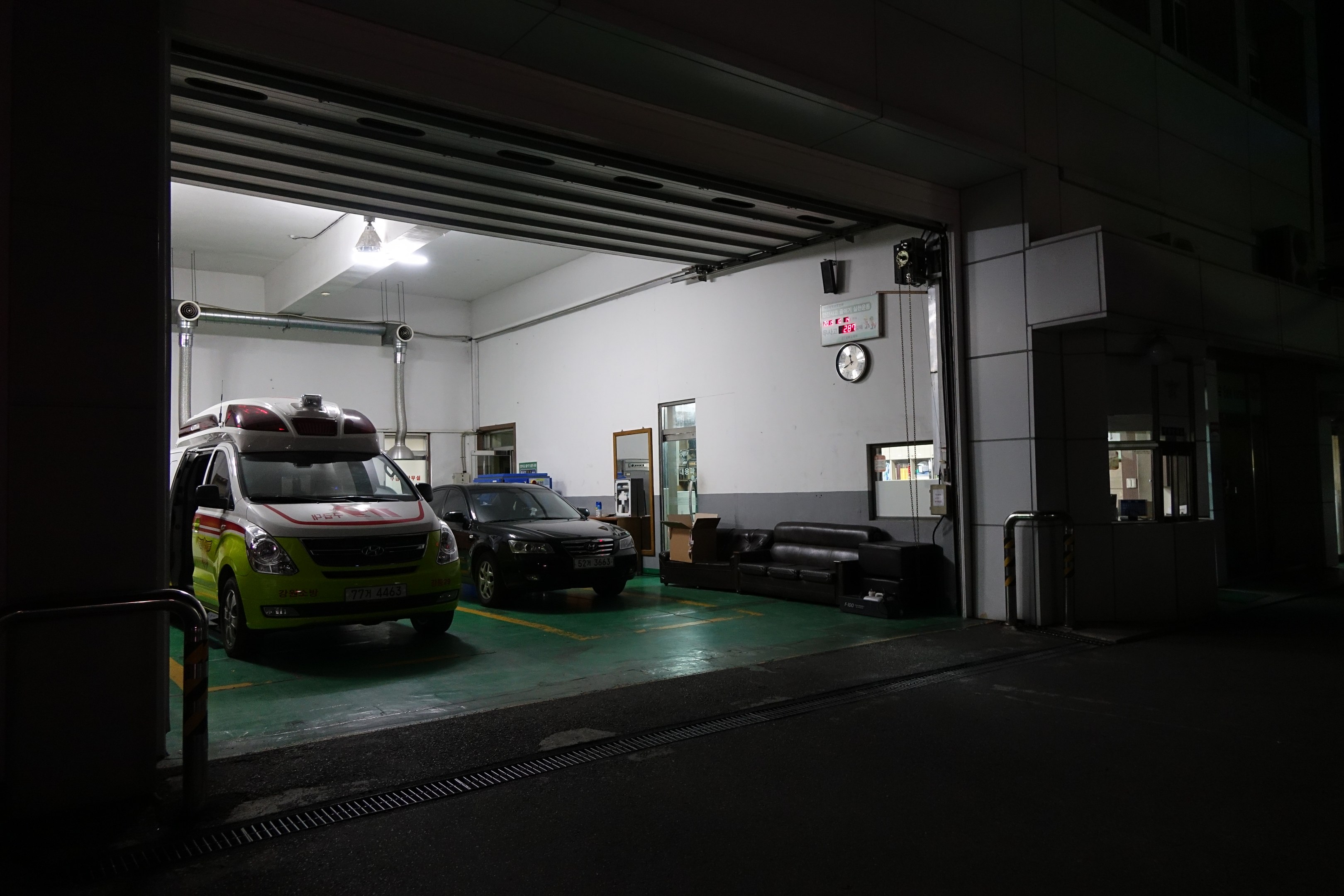Ambulanz parkt nachts in einem Gebäude, umgeben von Möbeln und Equipment.