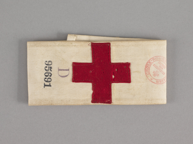 Erste-Hilfe-Set mit rotem Kreuzsymbol auf einem Stoffbeutel, der auf einer Oberfläche liegt.
