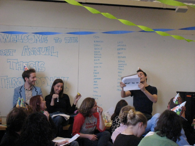 Eine Gruppe von Menschen feiert ihren ersten jährlichen Thesendurchwurf, mit Bändern auf dem Dach und einigen Individuen mit Mützen.